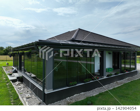 Modern single story house with glass porch and large lawn at sunset in rural setting Modern single story house with glass porch and large lawn at sunset in rural setting 142904054