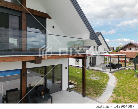 Modern family home with glass balcony and spacious patio in a suburban neighborhood 142904097
