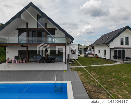 Modern family home with swimming pool and spacious backyard patio overlooking contemporary architecture Modern family home with swimming pool and spacious backyard patio overlooking contemporary architecture 142904117