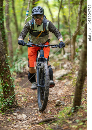 Mountain biking cyclist on a narrow forest trail enjoying an active outdoor adventure Mountain biking cyclist on a narrow forest trail enjoying an active outdoor adventure 142904796