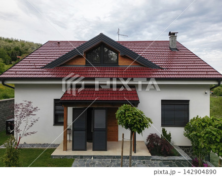 Modern countryside house with red metal roof, front porch and landscaped garden in spring daylight 142904890