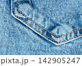 Blue denim pocket with golden double stitching and a pointed corner on a textured twill background 142905247
