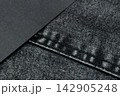 Dark gray paper overlapping a charcoal denim pocket with stitched edges and a diagonal background divide 142905248