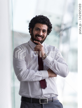 Smiling businessman portrait in office wearing white shirt and red tie, confident professional expression Smiling businessman portrait in office wearing white shirt and red tie, confident professional expression 142905489
