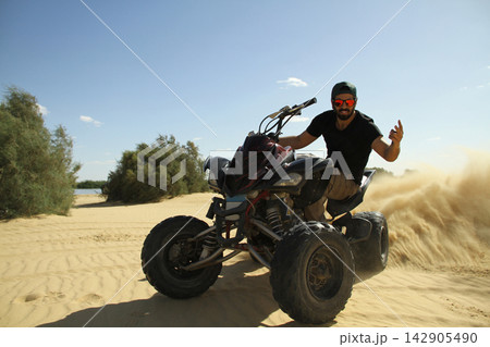 Young quad bike rider doing wheelie in desert 142905490