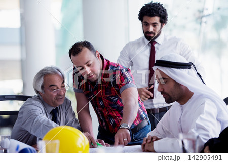 Multicultural business team collaborating on a construction project plan in a modern office meeting 142905491