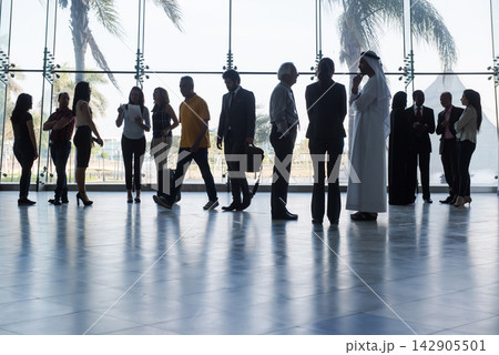 Business people networking and waiting in a spacious glass lobby with palm trees outside Business people networking and waiting in a spacious glass lobby with palm trees outside 142905501