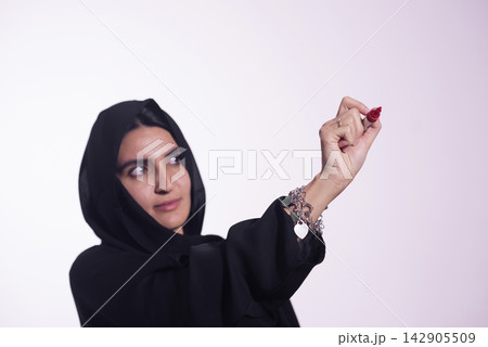 Woman wearing hijab and abaya writing with red marker for presentation or brainstorming 142905509