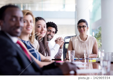 Business team meeting in modern boardroom with diverse professionals and female leader smiling Business team meeting in modern boardroom with diverse professionals and female leader smiling 142905554
