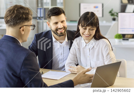 Realtor presenting property options to couple at office consultation with laptop Realtor presenting property options to couple at office consultation with laptop 142905602