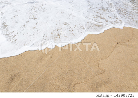 Sea wave foam on golden sand beach background Sea wave foam on golden sand beach background 142905723