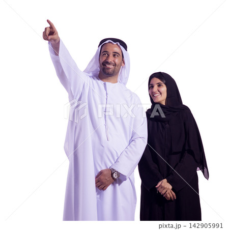 Smiling Emirati couple in traditional clothing pointing forward and looking toward the future Smiling Emirati couple in traditional clothing pointing forward and looking toward the future 142905991