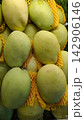 Close-up of fresh green and yellow mangoes with yellow protective foam mesh sleeves 142906146