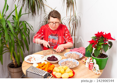 Woman is deboning herring at kitchen table to prepare traditional Christmas salad known as Herring Under Fur Coat, Ukrainian or Russian Christmas salad Shuba Woman is deboning herring at kitchen table to prepare traditional Christmas salad known as Herring Under Fur Coat, Ukrainian or Russian Christmas salad Shuba 142906544