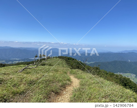 緑の稜線を進む登山道と幾重にも連なる夏の山並み 142906784