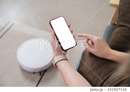 Cropped hand using smartphone to control smart robot vacuum Cropped hand using smartphone to control smart robot vacuum 142907316