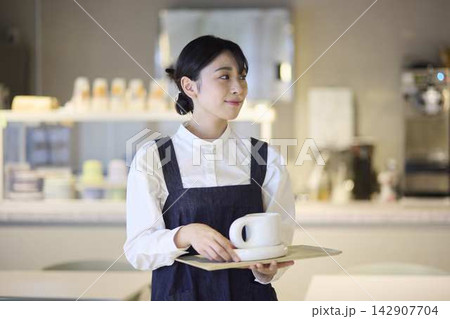 カフェでコーヒーを提供する女性スタッフ 142907704