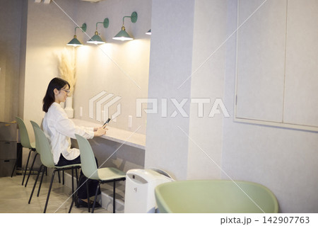 カフェのカウンター席でスマートフォンを見る女性 カフェのカウンター席でスマートフォンを見る女性 142907763