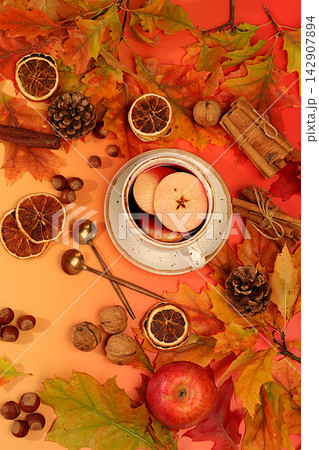 Abstract seasonal composition and still life with autumn greeting card, vibrant autumn banner featuring a cup of tea or mulled wine, maple leaves, pine cones, nuts, cinnamon, star anise, Abstract seasonal composition and still life with autumn greeting card, vibrant autumn banner featuring a cup of tea or mulled wine, maple leaves, pine cones, nuts, cinnamon, star anise, 142907894