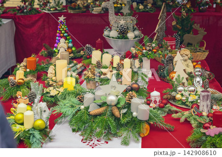 Christmas Decorations, Candle Arrangements. Christmas decorations with candles, evergreen branches, pine cones and colorful ornaments, festive market. Handmade holiday traditional arrangements Christmas Decorations, Candle Arrangements. Christmas decorations with candles, evergreen branches, pine cones and colorful ornaments, festive market. Handmade holiday traditional arrangements 142908610