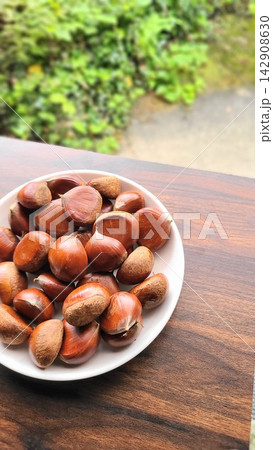 秋の味覚 緑を背景に皿に盛られた採れたての栗 秋の味覚 緑を背景に皿に盛られた採れたての栗 142908630