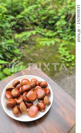 秋の味覚 緑を背景に皿に盛られた採れたての栗 142908635