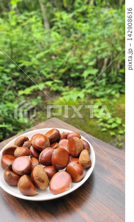 秋の味覚 緑を背景に皿に盛られた採れたての栗 秋の味覚 緑を背景に皿に盛られた採れたての栗 142908636