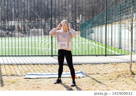 Young woman warming up before training outdoors in a sports ground Young woman warming up before training outdoors in a sports ground 142909032
