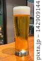 冷えた生ビールのグラスと木製テーブル 142909144