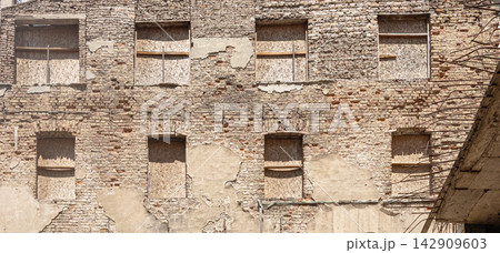 Old brick building facade with boarded up windows Old brick building facade with boarded up windows 142909603
