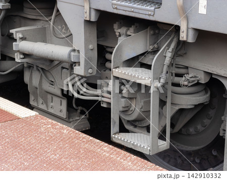 A close view of a metal access ladder attached to a heavy industrial train bogie, emphasizing railway maintenance engineering and the robust mechanical design of transit systems 142910332