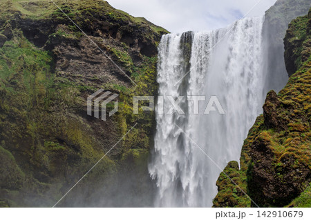Skogafoss Waterfall Flowing Between Moss Covered Cliffs in Southern Iceland Skogafoss Waterfall Flowing Between Moss Covered Cliffs in Southern Iceland 142910679
