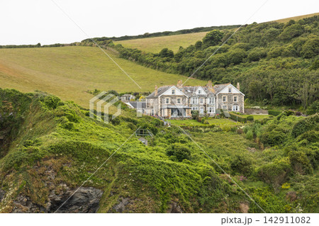 Traditional coastal countryside house nestled in rolling green hills 142911082