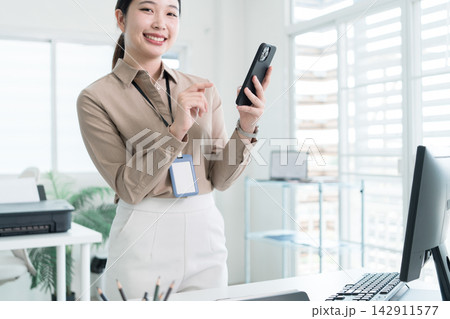 Young Businesswoman Working at Office Desk While Managing Documents and Mobile Communication. Young Businesswoman Working at Office Desk While Managing Documents and Mobile Communication. 142911577