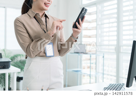 Young Businesswoman Working at Office Desk While Managing Documents and Mobile Communication. Young Businesswoman Working at Office Desk While Managing Documents and Mobile Communication. 142911578