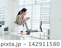 Young Businesswoman Working at Office Desk While Managing Documents and Mobile Communication. 142911580