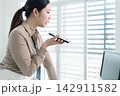 Young Businesswoman Working at Office Desk While Managing Documents and Mobile Communication. 142911582