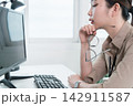 Young Businesswoman Working at Office Desk While Managing Documents and Mobile Communication. 142911587