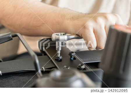 A hand tightens a bolt on an office chair using a metal ratchet wrench, showcasing assembly, repair, or maintenance tasks in a professional workspace setting for home or business usage 142912095