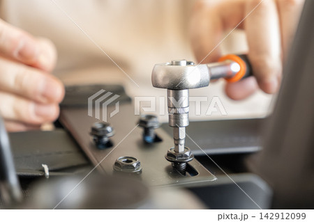 Person assembling a modern office chair using a steel ratchet tool to tighten black bolts, illustrating the home furniture construction process in a DIY project for interior renovation 142912099