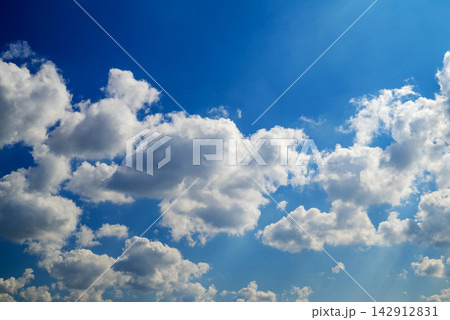 fluffy cloud masses filling the blue sky with soft sunlight rays shining through fluffy cloud masses filling the blue sky with soft sunlight rays shining through 142912831