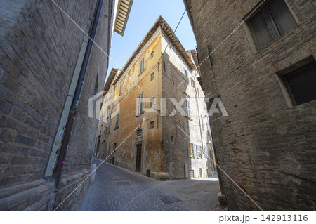 A narrow, cobblestone street in Urbino, Italy 142913116