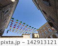Colorful triangular flags are strung across a small square in Urbino, Italy 142913121