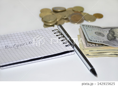 notepad with notes, pen, dollars and coins on a white background notepad with notes, pen, dollars and coins on a white background 142915625