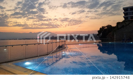 Swimming pool by the sea during a beautiful sunset 142915748