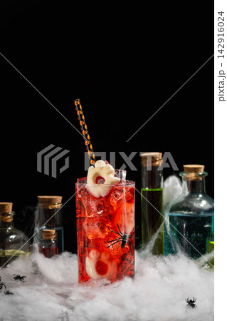 Spooky Halloween cocktail drink with spider and ghost garnish in eerie potion bottles setup Spooky Halloween cocktail drink with spider and ghost garnish in eerie potion bottles setup 142916024