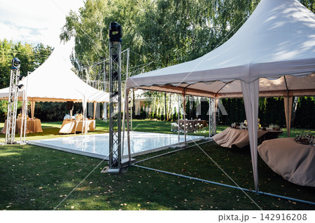 Elegant wedding table setting with floral centerpiece and candles under a marquee tent. 142916208