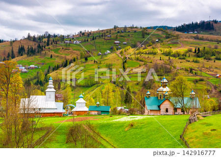 agricultural field on hillside in mountains near village in dappled light. wooden fence on the slope. Synevyr national park, TransCarpathia, Ukraine. cloudy sky in springtime agricultural field on hillside in mountains near village in dappled light. wooden fence on the slope. Synevyr national park, TransCarpathia, Ukraine. cloudy sky in springtime 142916777