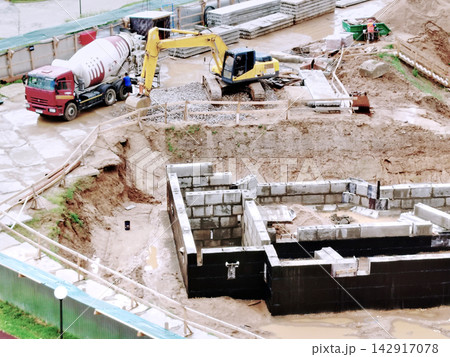 Construction Site With Excavator And Cement Truck Building Foundation In Muddy Urban Work Zone. Construction Site With Excavator And Cement Truck Building Foundation In Muddy Urban Work Zone. 142917078
