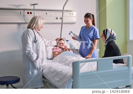 Caring medical staff support young patient in a modern hospital room during an uplifting check-up visit Caring medical staff support young patient in a modern hospital room during an uplifting check-up visit 142918069